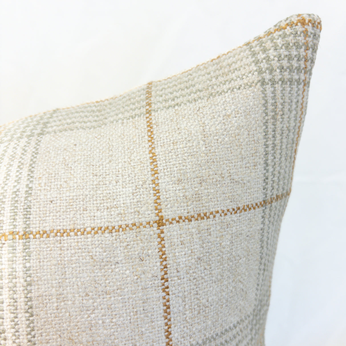 Textured pillow with a subtle windowpane plaid pattern on a light background